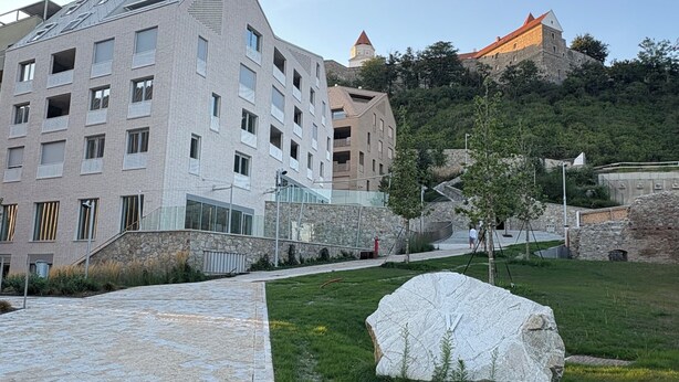 Ein modernes Gebäude mit einer Stein-Fassade und einem großen Felsen im Vordergrund.