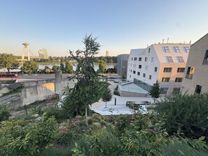 Un edificio moderno con fachada de vidrio, un río al fondo y un puente.