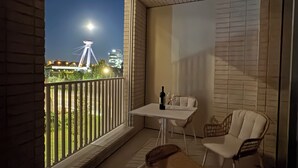 Ein Balkon mit Tisch, Stühlen, einer Flasche und einem Weinglas.