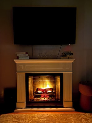 A fireplace with a television mounted above it, a mantel with books, and a potted plant to the side. - The Royal Suite under the castle with river views & private parking (Bratislava-Staré Mesto)