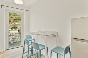 Una cocina moderna con encimera blanca, dos sillas azules y un refrigerador blanco.