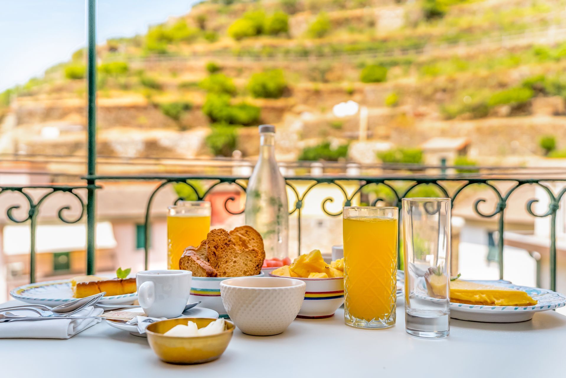 Taula amb articles per esmorzar, com pa, fruita i begudes, davant d'una vista panoràmica de la ciutat.