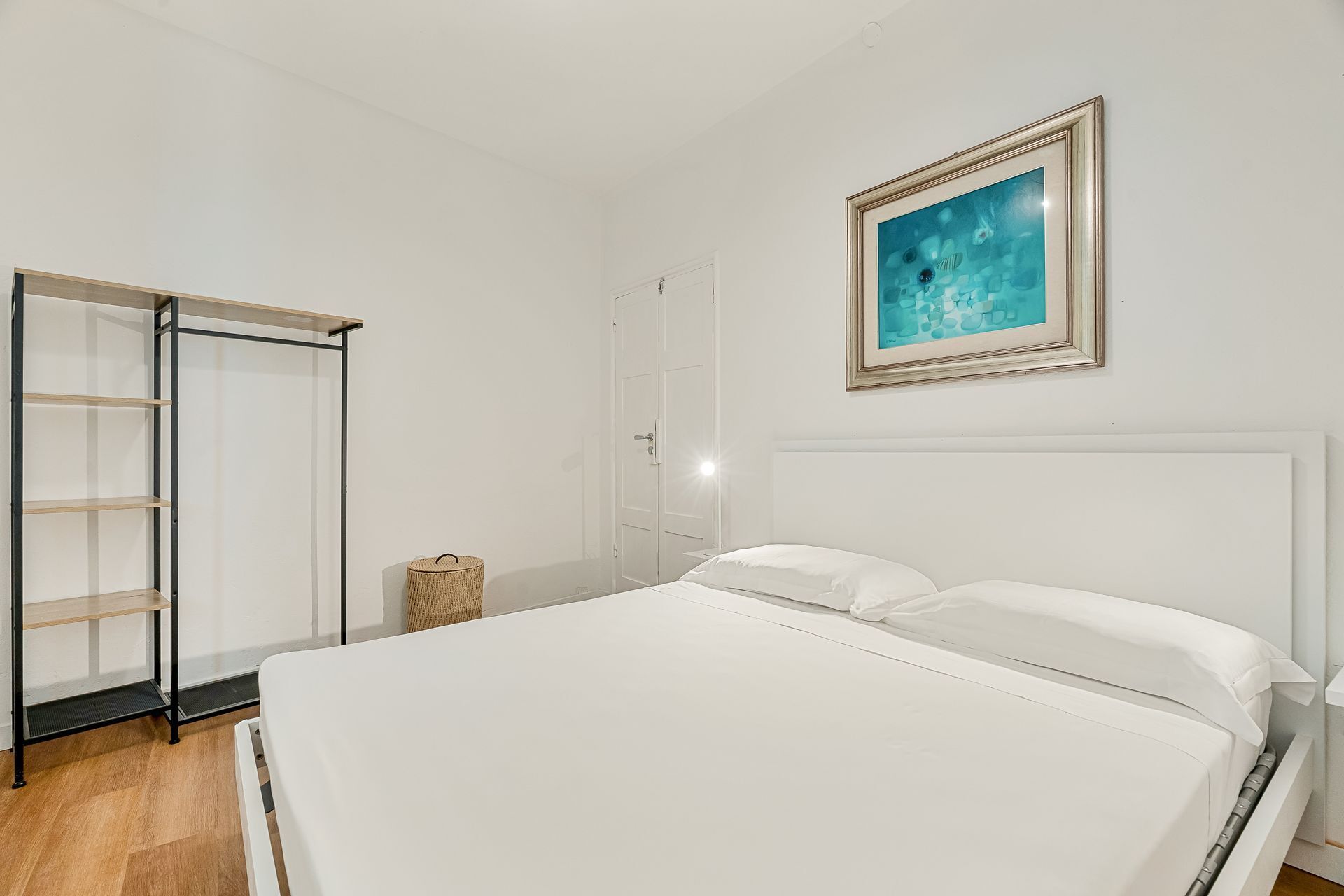 A bedroom with a bed, a wardrobe, and a framed picture on the wall.