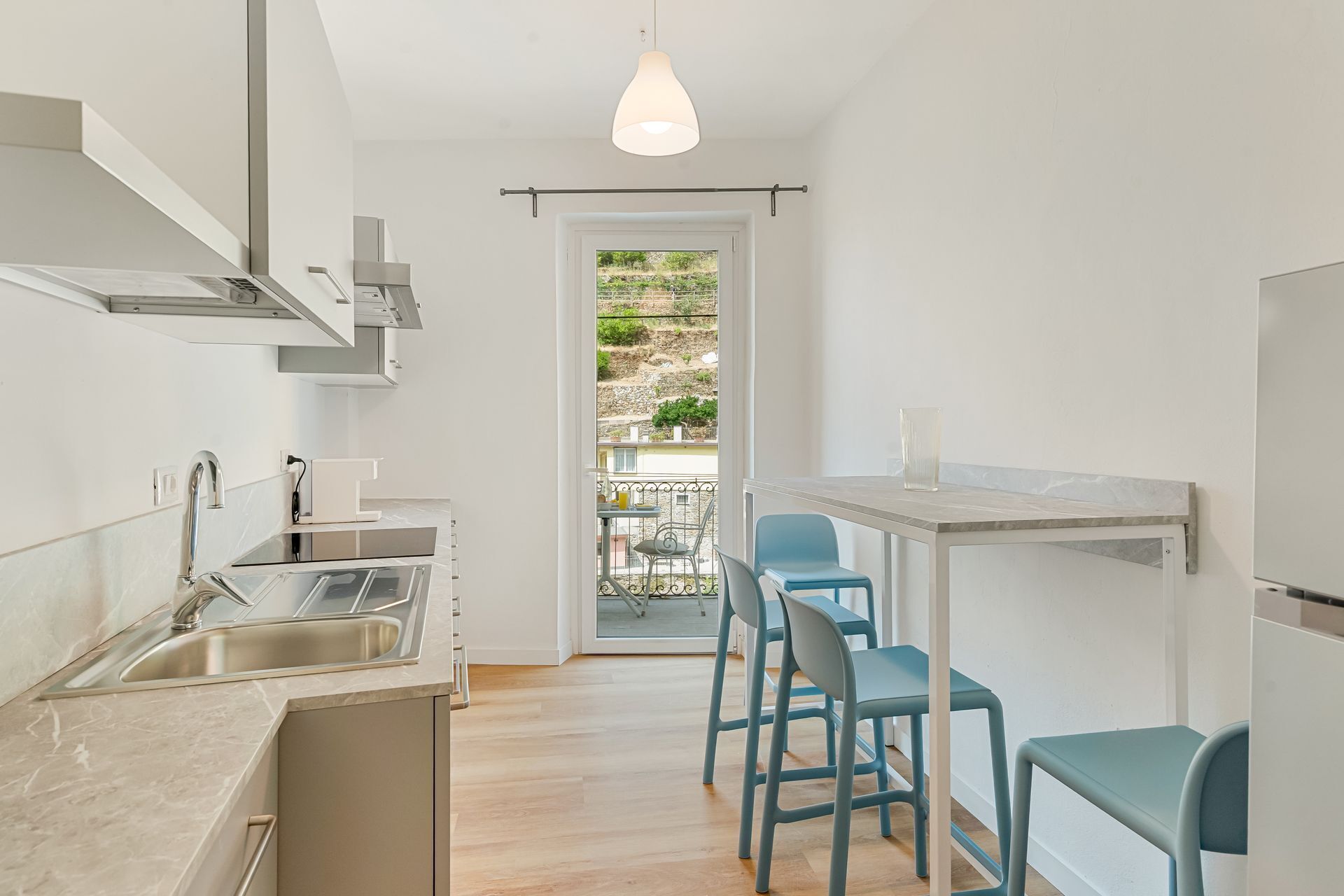 Una cocina moderna con un lavamanos, estufa y comedor con sillas.