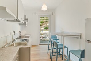 A modern kitchen with a sink, stove, and dining area with chairs.