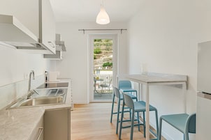 Una cocina moderna con un lavamanos, estufa y comedor con sillas.