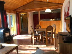 A wooden interior with a dining table, chairs, a TV, and a fireplace. - Komfortabler Doppelbungalow mit Terrasse im Ferienpark Mirow (Mirow)