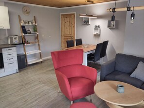 Ein modernes Wohnzimmer mit einem roten Sessel, einem grauen Sofa, einem Holzesstisch und einem kleinen Couchtisch.