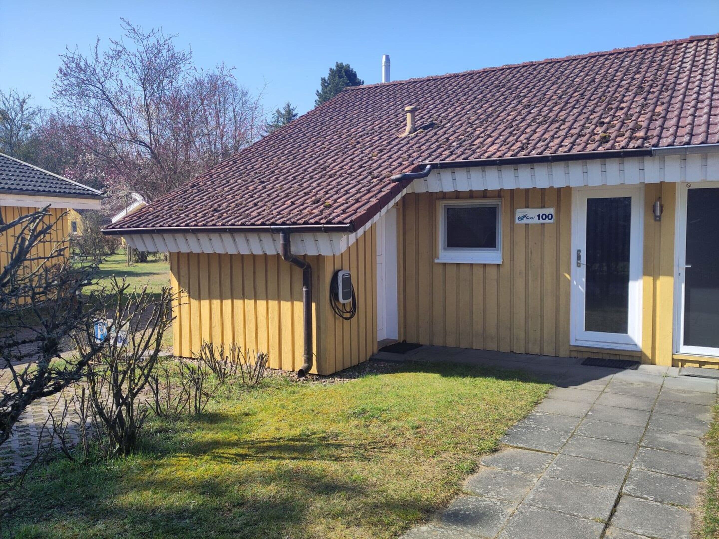A yellow building with a tiled roof, a small window, and a door.
