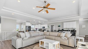 A spacious living room with a sectional sofa, a round coffee table, and a ceiling fan. - Endless Summer, Oceanfront, 8 Bdrm, Pvt. Htd Pool, Pvt. Direct Beach Access (Holden Beach)