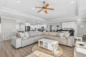 Ein großzügiges Wohnzimmer mit Ecksofa, rundem Couchtisch und Deckenventilator.