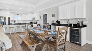 A modern kitchen with white cabinetry, a wooden dining table, and a built-in oven. - Endless Summer, Oceanfront, 8 Bdrm, Pvt. Htd Pool, Pvt. Direct Beach Access (Holden Beach)