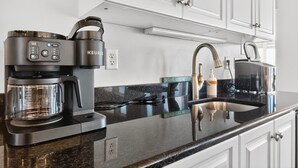 A modern kitchen with a coffee maker, a kettle, and a sink. - Endless Summer, Oceanfront, 8 Bdrm, Pvt. Htd Pool, Pvt. Direct Beach Access (Holden Beach)