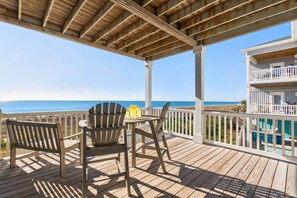 A wooden deck with Adirondack chairs and a table, overlooking a beach and a pool. - Endless Summer, Oceanfront, 8 Bdrm, Pvt. Htd Pool, Pvt. Direct Beach Access (Holden Beach)