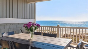 A covered outdoor seating area with a table and chairs, overlooking a beach. - Endless Summer, Oceanfront, 8 Bdrm, Pvt. Htd Pool, Pvt. Direct Beach Access (Holden Beach)