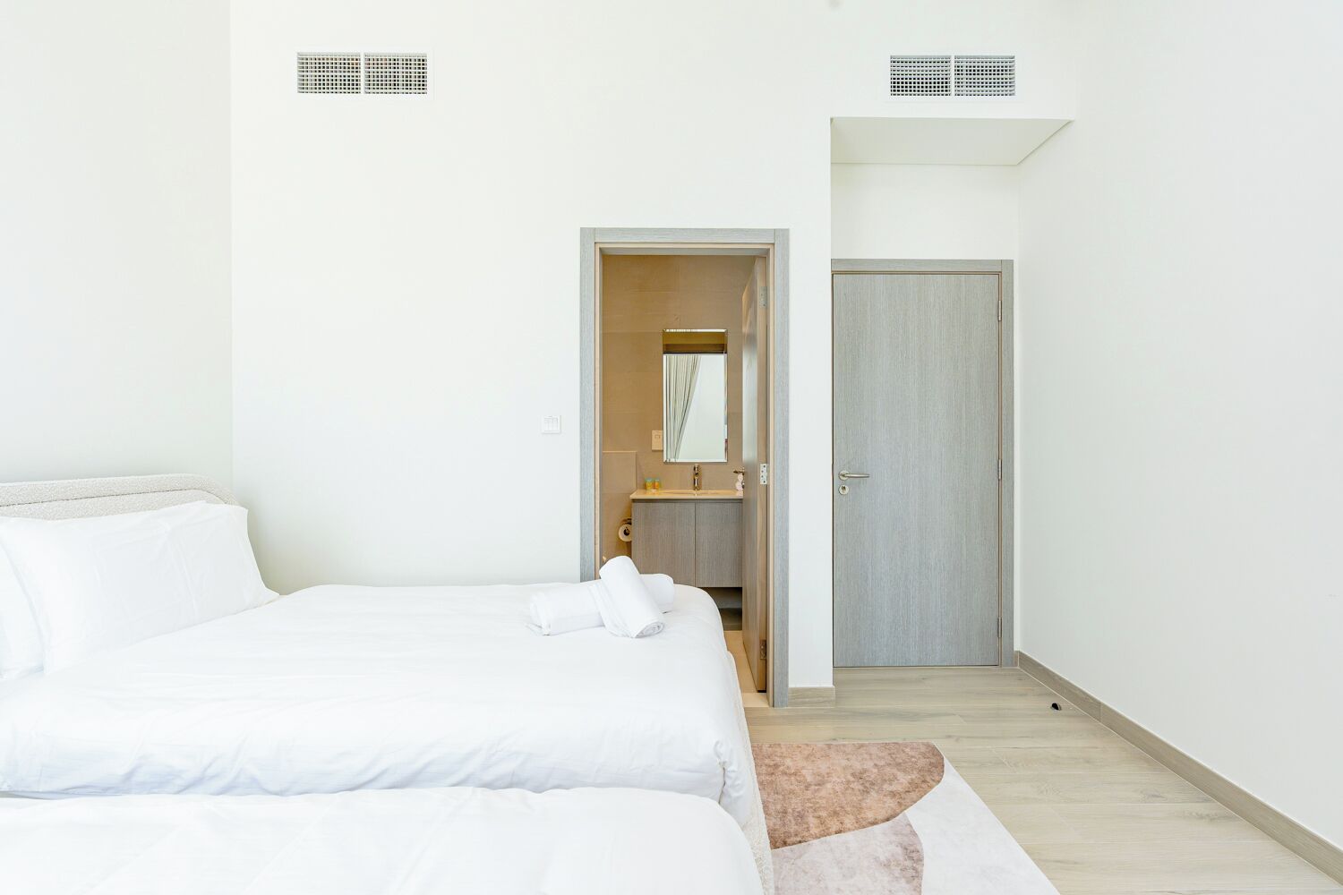 Um quarto com uma cama, um banheiro com um espelho e uma porta.