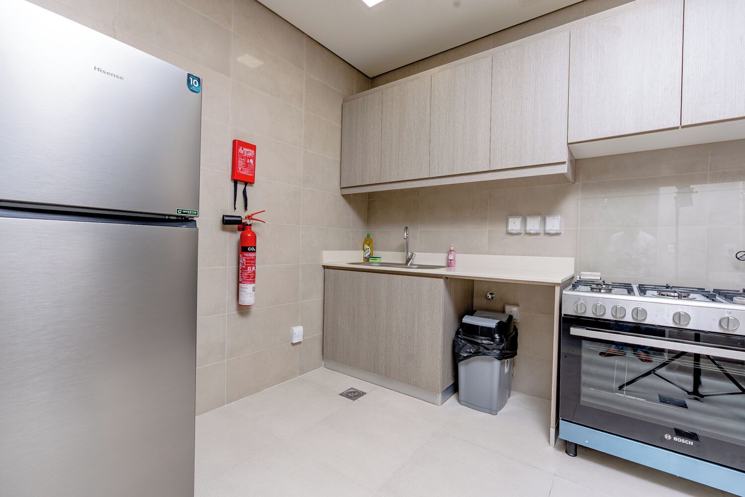 Een moderne keuken met een roestvrijstalen koelkast, een gasfornuis van Bosch en kastjes van licht hout.