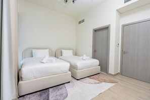 A hotel room with two beds, a door, and a light-colored rug. - Coastal Family Villa in Marbella RAK (Ras Al-Khaimah)