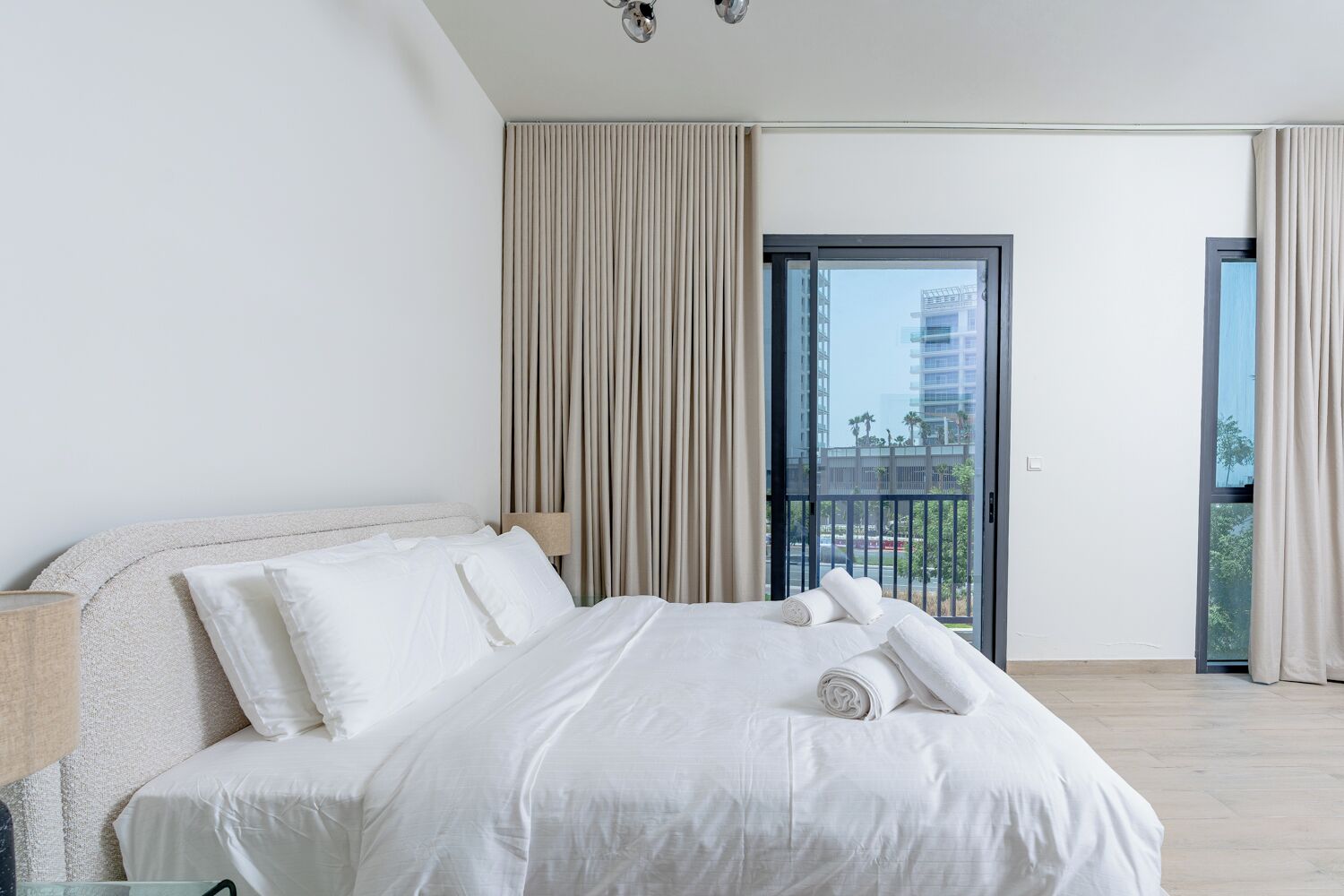A hotel room with a bed, a view of the city, and a balcony.