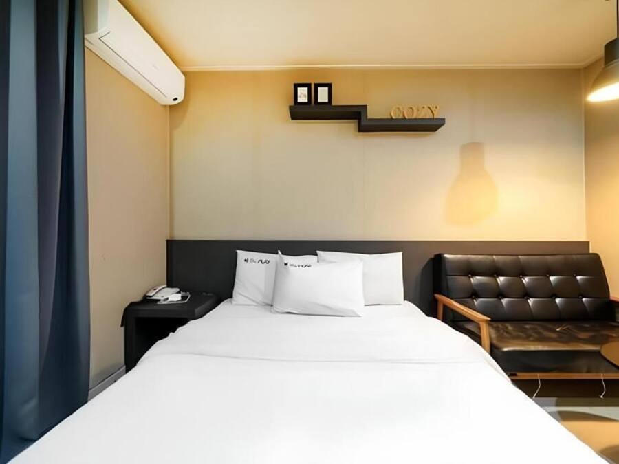 Habitación de hotel con cama, mesita de noche, teléfono, sofá y una pequeña mesa.