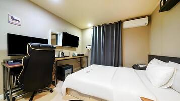 Una camera d'albergo con un letto, una scrivania con un computer, una sedia e una televisione.