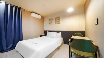 Quarto de hotel com cama, escrivaninha, cadeira e cortina.