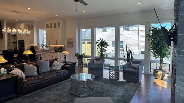 Ein geräumiges Wohnzimmer mit Sofa, Sesseln, einem Couchtisch und einem Essbereich mit einer Chandelüster.