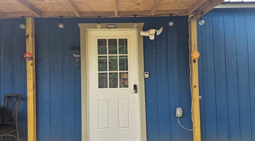 A white door with a window, a mailbox, and a small outdoor light fixture.