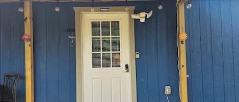 A white door with a window, a mailbox, and a small outdoor light fixture.