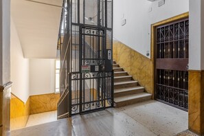Eine Treppe mit einem Metallgitter oben, Marmorstufen und eine Wand mit einem dekorativen Muster.