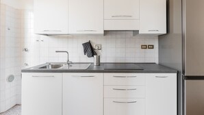 Eine moderne Küche mit weißen Schränken, einem Edelstahlkühlschrank und einer Arbeitsplatte aus Granit.