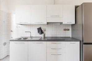 A modern kitchen with white cabinets, a stainless steel refrigerator, and a granite countertop. - Irnerio Apts - Olive Green by Wonderful Italy (Bologna)