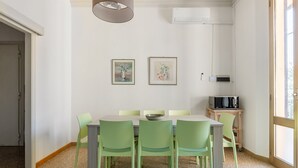 Ein Essbereich mit Tisch und Stühlen, einer Klimaanlage und Kunstwerken an der Wand.