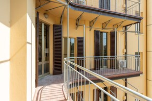 A balcony with a metal railing, a window with a shutter, and a door leading to an interior space. - Irnerio Apts - Olive Green by Wonderful Italy (Bologna)