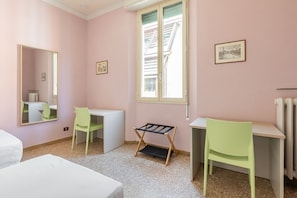 A room with two desks, two chairs, a bed, a radiator, and a window with a view of buildings. - Irnerio Apts - Olive Green by Wonderful Italy (Bologna)