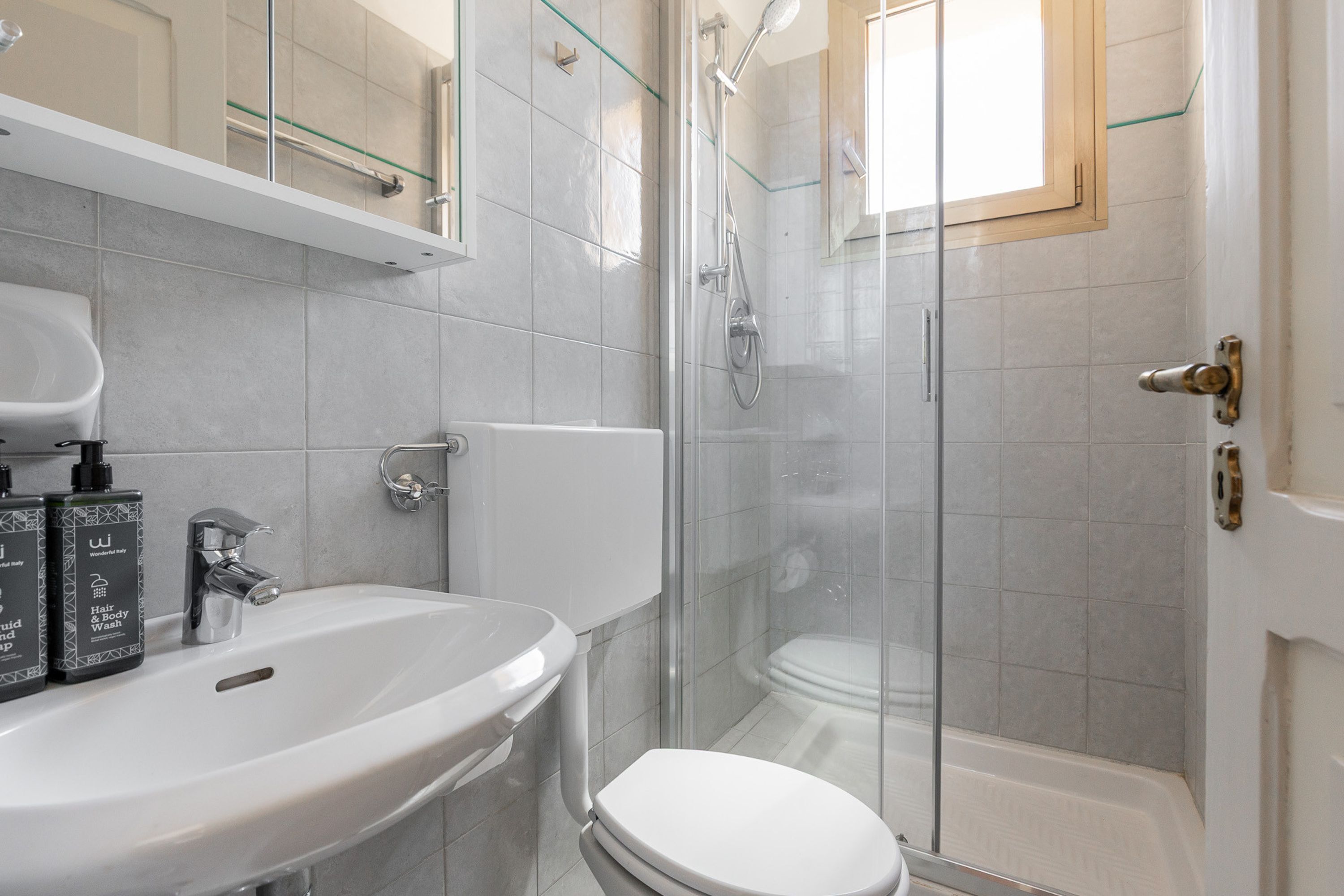 Une salle de bain avec un lavabo blanc, une douche en verre et des toilettes.