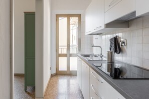 A kitchen with white cabinets, a stainless steel sink, and a door leading to a balcony. - Irnerio Apts - Olive Green by Wonderful Italy (Bologna)