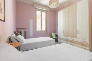 A bedroom with two beds, a radiator, a window, and a wardrobe. - Irnerio Apts - Olive Green by Wonderful Italy (Bologna)