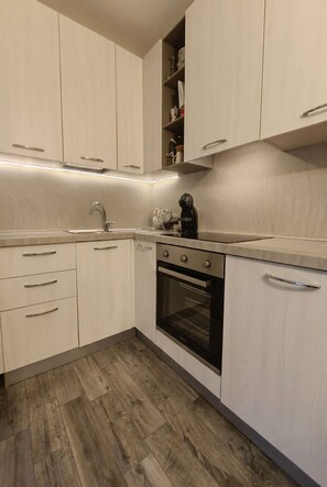 A kitchen with light-colored cabinets, a stainless steel sink, a built-in oven, and a coffee maker on the countertop. - Casa Panorama — 50 square meters of garden with a hot tub and a view of the lake (Laino)
