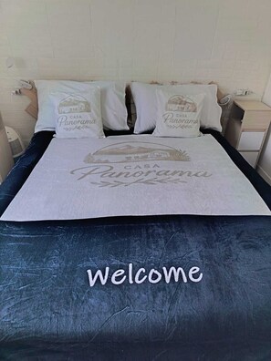 A bed with a white bedspread featuring the text 'CASA Panorama' and a pillow with the same text. - Casa Panorama — 50 square meters of garden with a hot tub and a view of the lake (Laino)