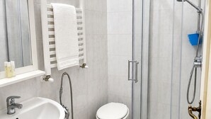 A bathroom with a glass-enclosed shower, a sink, a toilet, and a towel rack. - Elegant apartment just a stone's throw from Piazza del Campo (Siena)