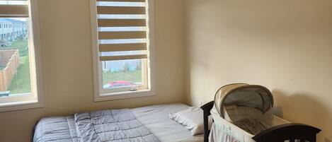 A bedroom with a single bed, a nightstand, and a window with blinds.