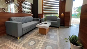 A modern living room with a grey sofa, a coffee table, and a potted plant.