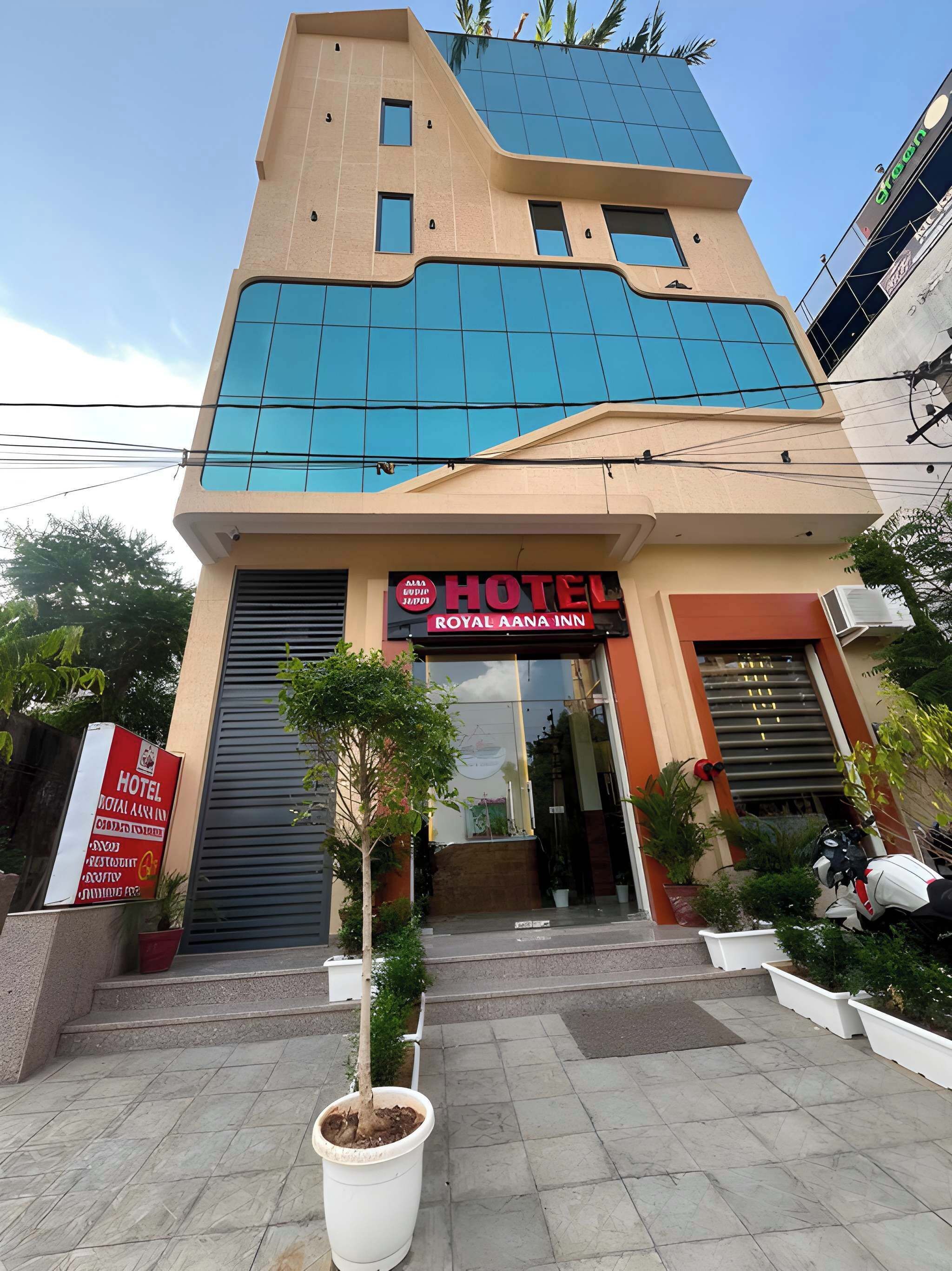 A hotel with a modern facade, a prominent entrance, and a sign indicating it is the Royal Aana Inn.