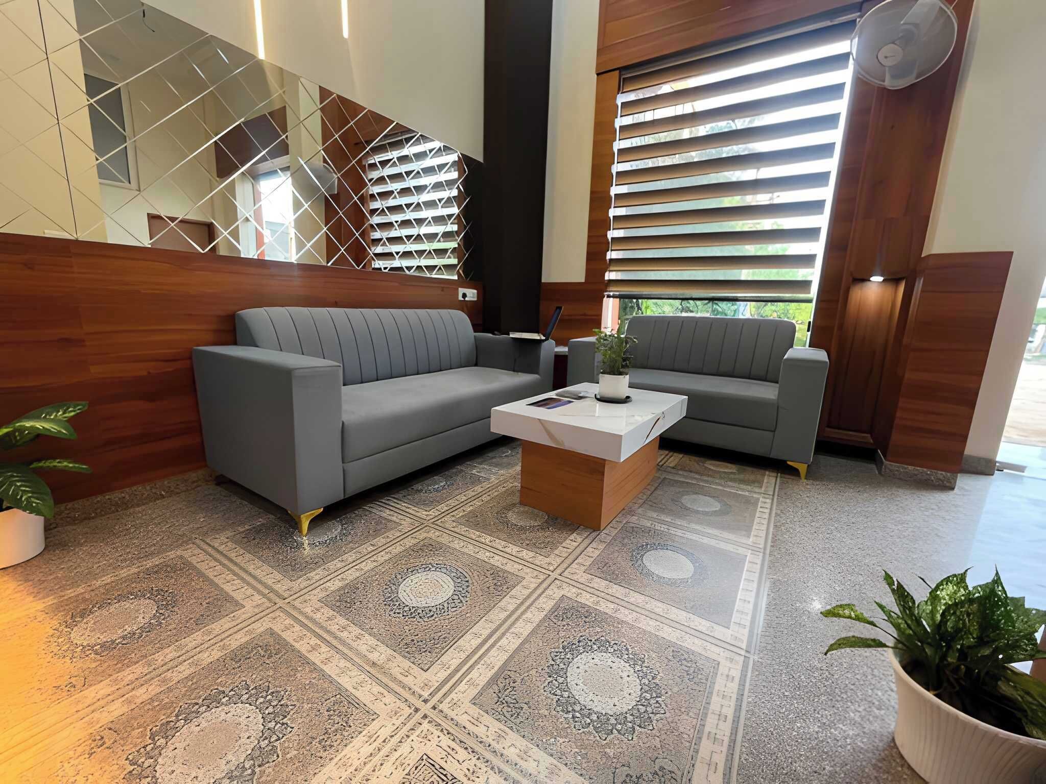 A modern lobby with a grey sectional sofa, a coffee table, and a patterned rug.