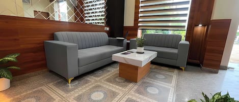 A modern lobby with a grey sectional sofa, a coffee table, and a patterned rug.