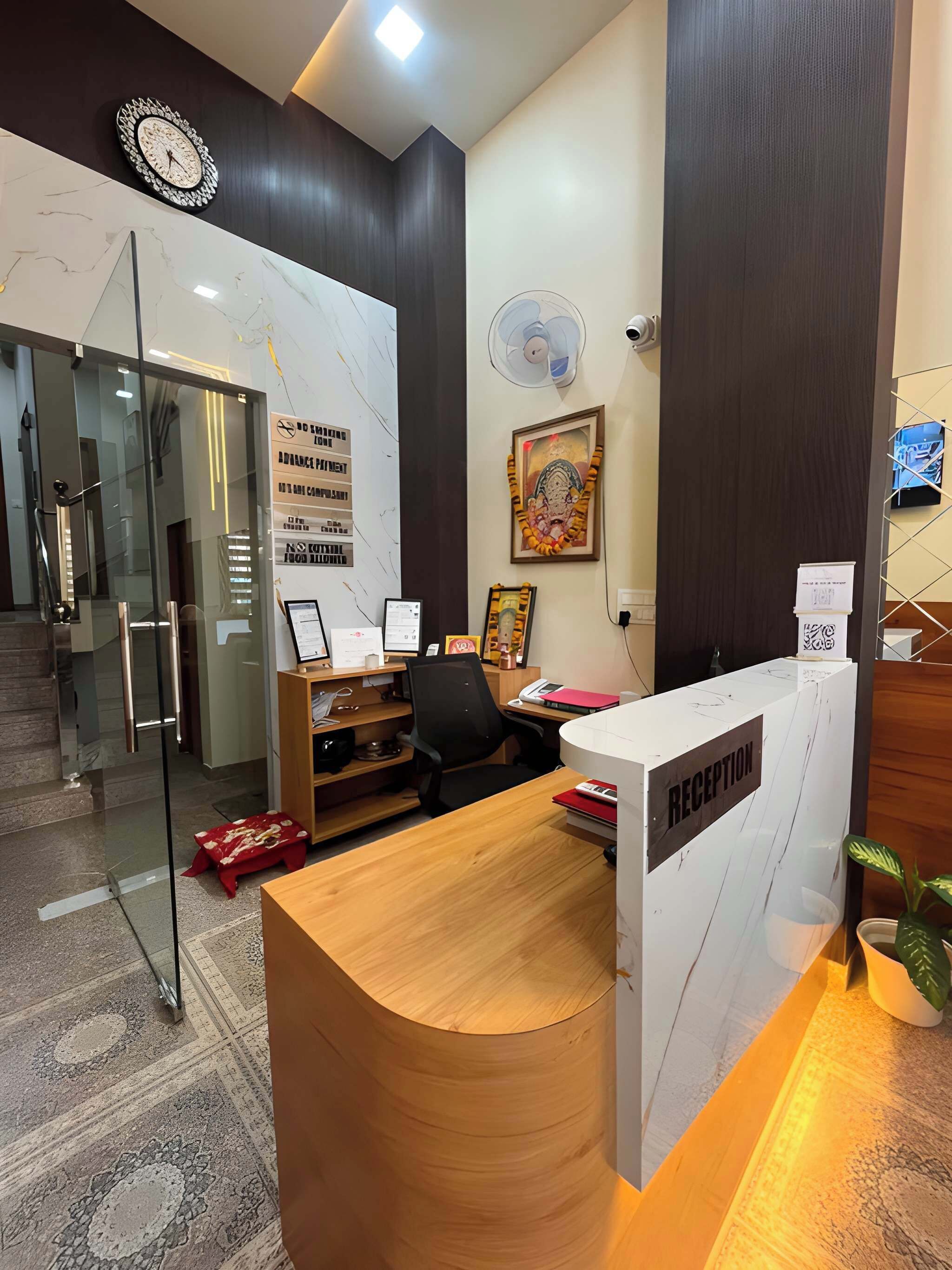 A reception desk with a 'RECEPTION' sign, a clock, and a framed picture on the wall.