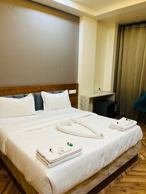 A hotel room with a large bed, a desk, a chair, and a bathroom visible through an open door. - Hotel Royal Aana Inn (Jaipur)