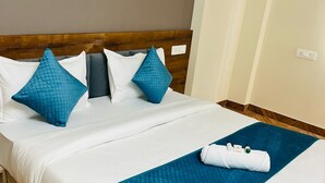 A neatly made bed with a wooden headboard, white bedding, and two blue pillows.