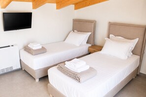 A hotel room with two beds, a TV mounted on the wall, and a heater. - Zidros Apartments Maisonette Apartment 4 (Sfakaki)